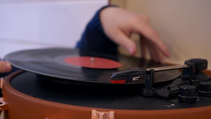 Close-up put a vinyl record in the turntable and lower the needle to listen to classical music. A vintage turntable that spins a vinyl record. Listening to music in the 20th century.