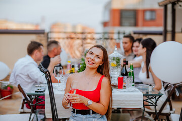 Woman in red clothes posing with glass of champagne against friends background.