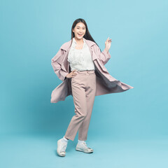 Young beautiful asian woman with smart casual cloth wearing pink coat smiling isolated on blue background