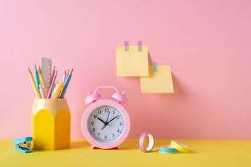 Back to school concept. Photo of colorful school supplies alarm clock adhesive tape pencil holder...