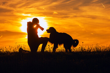 boy and hovie, two friends, silhouettes during sunset, a dog puts his paw on the photographer's knee