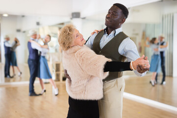 Elderly woman learning ballroom dancing in pair in dance studio