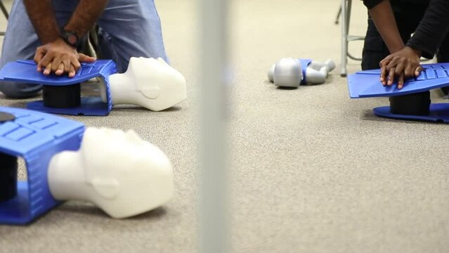 Staff practicing first aid cpr with AED machine and dummy dolls