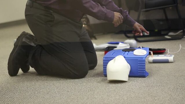 Staff practicing first aid cpr with AED machine and dummy dolls