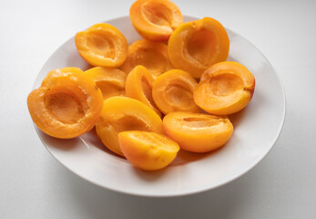 ripe, juicy apricots lie on a white plate. Energy boost, vitamins, ripe fruits, pesticides. Interruptions in the supply of fruits, imports of apricots
