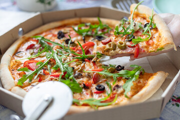 A woman takes a slice of delicious fresh pizza. Delicious pizza in a box