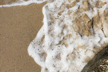 Beach sand sea water summer background. Sand beach desert texture. White foam wave sandy seashore top view.