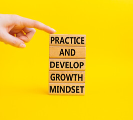 Practice and Develop growth mindset symbol. Wooden blocks with words Practice and Develop growth mindset. Beautiful yellow background. Businessma hand. Business concept. Copy space