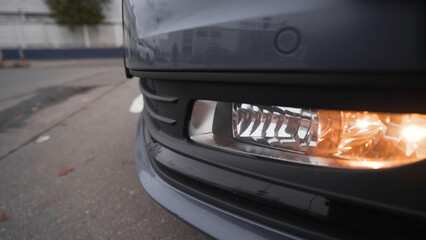 Close-up of headlights of modern car model. Action. Daytime running lights of new car. Beautiful front lights of new car in cloudy weather