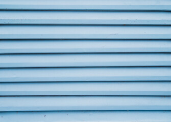 Fototapeta premium Abstract metal background of their shutters. Blue shutters on the door. Smooth horizontal lines. Texture of metal strips.