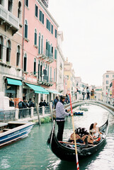 Fototapeta na wymiar Bride and groom are sailing in a gondola to the bridge on the canal in Venice