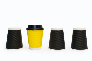 Disposable cardboard coffee cups on a white background. Three black and one yellow coffee cups. The concept of excellence and the ability to stand out and be different