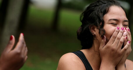 Two friends laughing and smiling outside. Interracial friendship, hispanic and african women