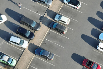 Aerial view of many colorful cars parked on parking lot with lines and markings for parking places and directions