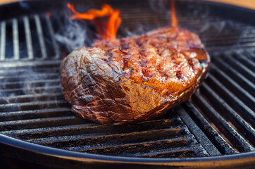 BBQ dry aged wagyu sirloin cap of rump beef steak grilled as close-up on a charcoal grill with fire and smoke