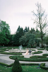 Bride and groom walk through the garden past the fountain. Lake Como, Italy