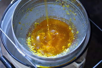 Filtering honey through a fine and large sieve.