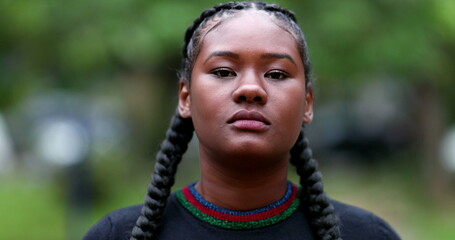 Serious young black woman walking forward. Portrait African girl outside
