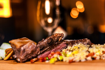 Closeup of pork ribs grilled with BBQ sauce and caramelized in honey. Tasty snack to beer on a wooden Board for filing on dark concrete background.