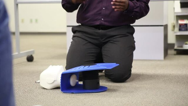 Staff practicing first aid cpr with AED machine and dummy dolls