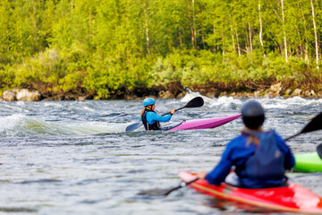 Whitewater kayaking, extreme sport rafting. Young woman in kayak sails mountain river