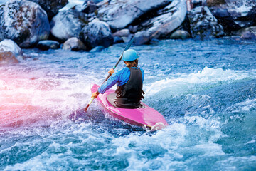 Whitewater kayaking, extreme sport rafting. Back view young woman in kayak sails mountain river