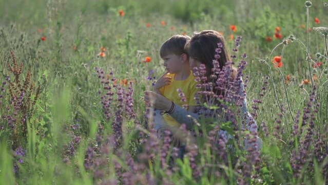Mother and son enjoy flowers sitting in a blossom meadow