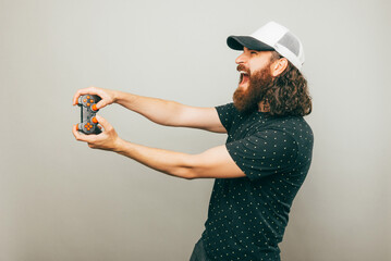 A photo of a young bearded man playing video games with a console