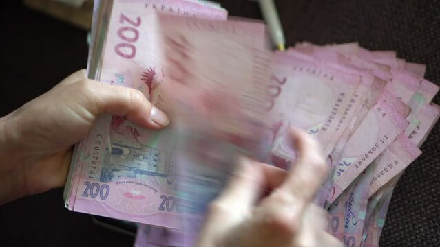 Female hans counting ukraininan hryvna  banknotes nominated 200.