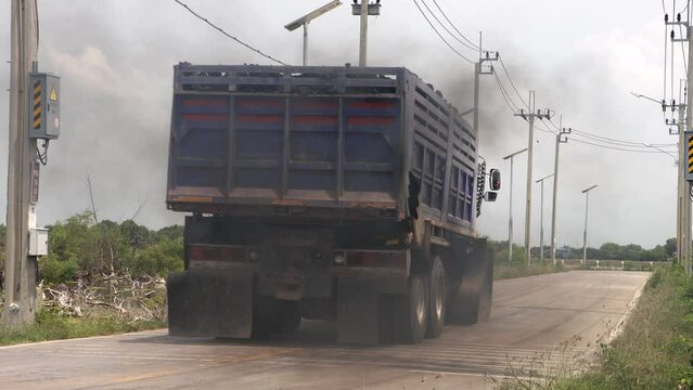 A loaded truck travels on the road with thick black smoke from the exhaust