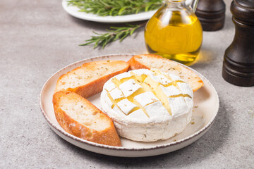 Baked camembert soft cheese. Grilled brie with toasts and rosemary. 