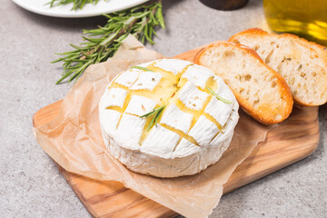Fototapeta na wymiar Baked camembert soft cheese. Grilled brie with toasts and rosemary. 