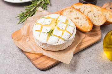 Baked camembert soft cheese. Grilled brie with toasts and rosemary. 