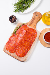 Chorizo sausage and salami, thin cut. Spanish salami on the wood background with spices, paprika, rosemary and olives. Spicy food. Antipasto and appetizer meat. 
