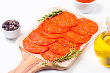 Chorizo sausage and salami, thin cut. Spanish salami on the wood background with spices, paprika, rosemary and olives. Spicy food. Antipasto and appetizer meat. 