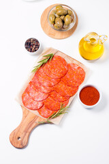 Chorizo sausage and salami, thin cut. Spanish salami on the wood background with spices, paprika, rosemary and olives. Spicy food. Antipasto and appetizer meat. 