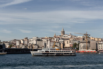 Fototapeta premium View of a traditional ferry boat on Golden Horn part of Bosphorus in Istanbul. Galata tower and Beyoglu district are in the view. It is a sunny summer day.