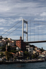 View of people walking by Bosphorus in Rumeli Hisari neighborhood on European side and FSM bridge in Istanbul. It is a sunny summer day. Beautiful travel scene.