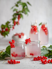 Jars of red currant kissel drink with leaves and berries on the table. Selective focus