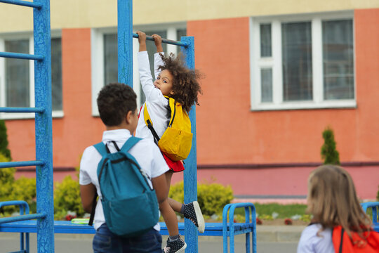 children play on the playground with backpacks, after school