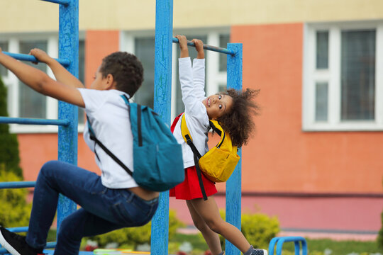 children play on the playground with backpacks, after school - Powered by Adobe