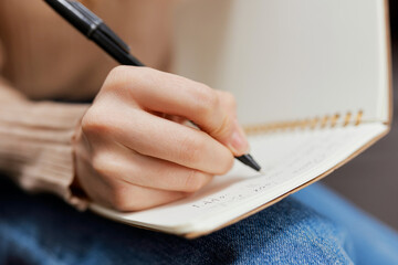 Closeup shot of hand blonde student lady with copybook sitting in sofa couch at modern living room...