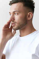 Fototapeta premium Portrait shot of handsome pensive romantic serious tanned man guy in basic t-shirt looks aside posing on white background. Fashion Style New Collection Offer. Copy space for ad. Model snap