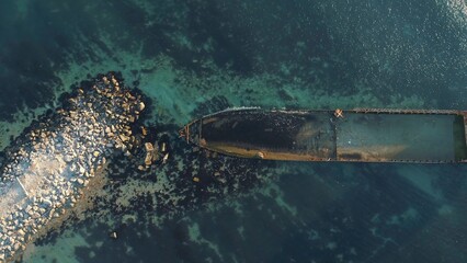 Aerial view of the rusty sunken ship stuck on a rocky shoal. Shot. Old seagoing vessel
