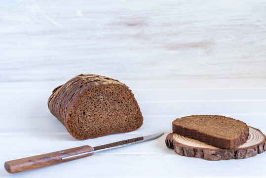Food background with dark bread, knife, cut board on wooden surface.