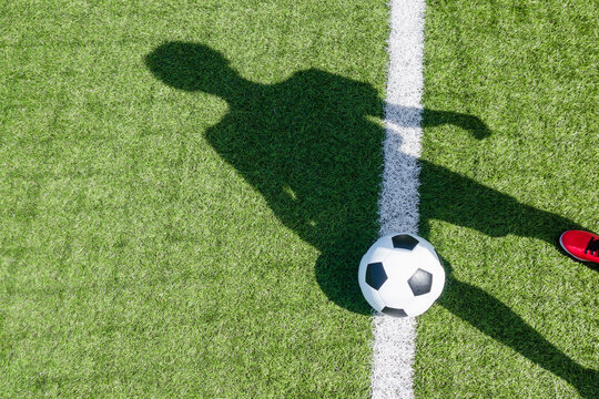 Fototapeta Soccer football sport background. Soccer ball and shadow of player on artificial turf soccer field in sunny day outdoors