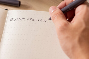 Man's hands writing in his bullet journal with a pen