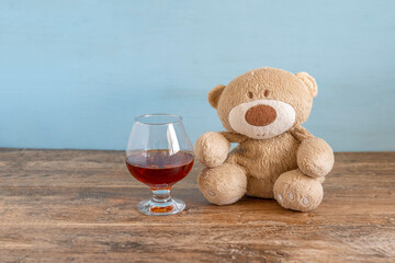 Bear toy and glass of cognac. Social problems concept. Children and alcohol.