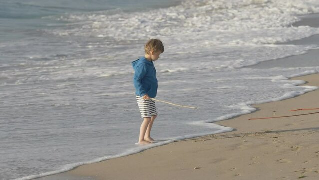 Sea waves washing the drawing of kid with wooden stick on beach sand