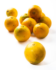 lot of yellow oranges on a white background one in the foreground the rest in the background